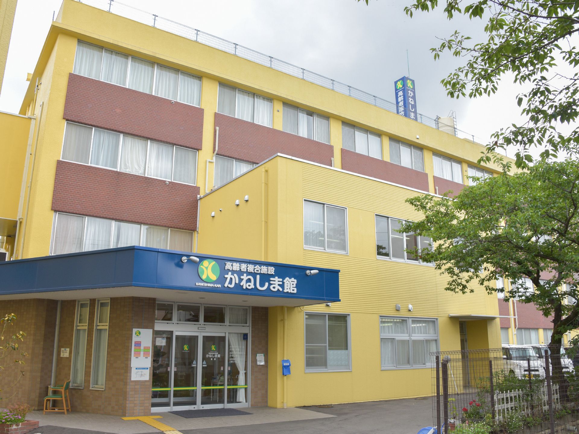 施設は4階建ての建物で、最上部の外周にはフェンスが設置されている。左側には上部に屋根が設置された入り口ドアがある。