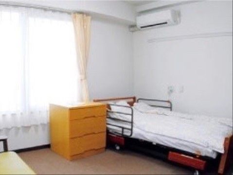 窓から日差しが入って明るい。柵とキャスターが付いたベッドが部屋の角に置かれている。室温はエアコンで調節することができる。