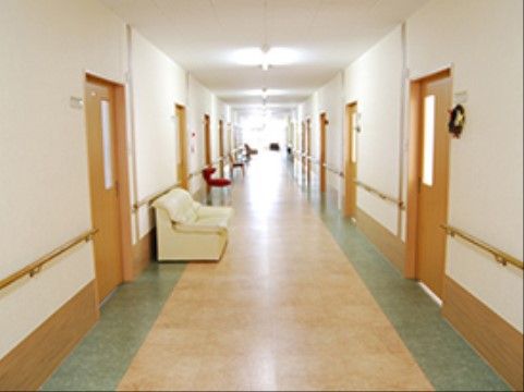 横幅の広い廊下には白いソファが置かれ、両側には居室がたくさん並んでいる。居室前の壁には、名札が取りつけられている。