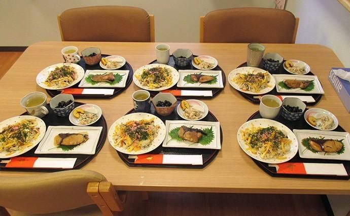 トレーにのせた一人分の食事が複数並んでいるテーブル