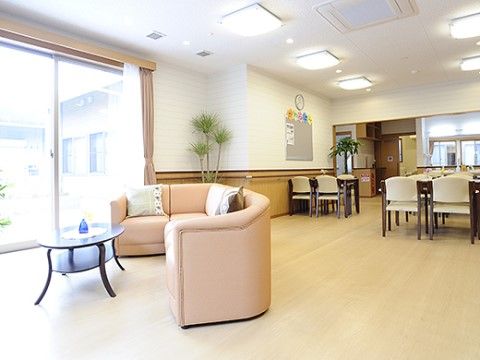 大きな掃き出し窓が備え付けられており、外の風や光を感じながら過ごせる。背の高い観葉植物も飾られている。