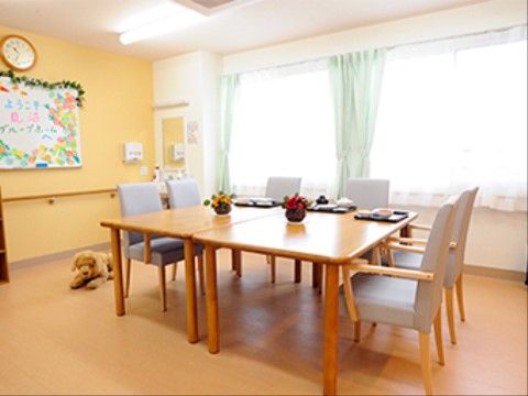 自然光が入ってくる明るいリビング。共有のテーブルを部屋の真ん中に並べて、入居者様の団欒スペースを作っている。
