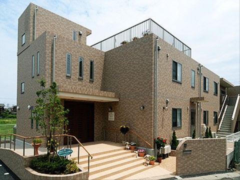 施設の外壁はモザイクタイル調になっている。玄関周りは植え込みや植木鉢を活用し、自然の彩りで装飾されている。