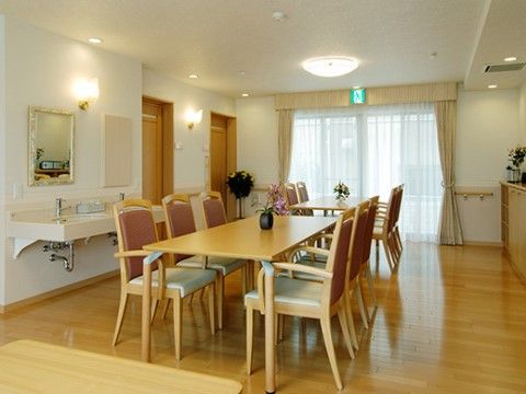 手洗い場の設けられたリビング。フローリングとダイニングテーブルは木調に統一され落ち着きがある。広い窓の上には非常口のマークが掲げられている。