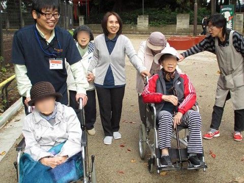 笑顔で外を歩く高齢者とスタッフ