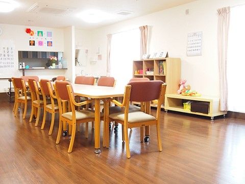 室内の床はフローリングになっており、長いテーブルの周りには手すり付きの椅子が置かれている。壁と天井は白色系である。