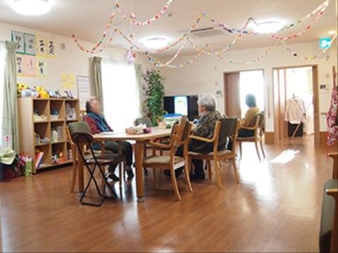 リビングの床はフローリングになっており、テーブル、手すり付きの椅子が備えられている。大きな窓があり、天井には照明が完備されている。