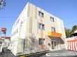 施設の建物は３階建てで、数多くの窓が設けられている。１階の玄関には屋根が設置され、前面には駐車スペースがある。