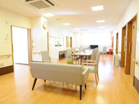 リビングの床はフローリングになっており、テーブルセット、ソファが置かれている。高い天井にはエアコン、照明設備が設置されている。