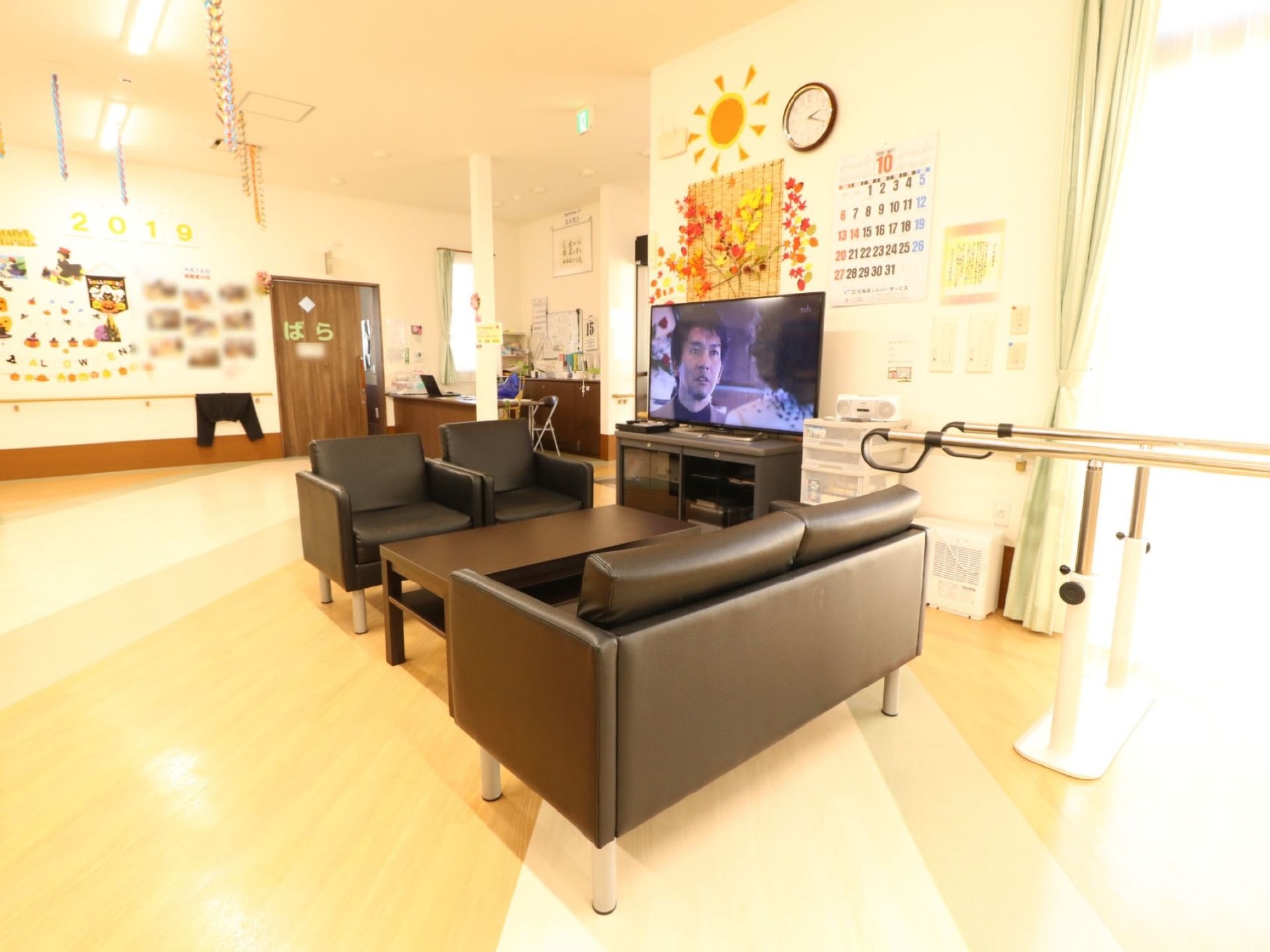 テレビ台のそばに、落ち着いた色合いのソファーとテーブルが設置されている。ゆったりとおしゃべりやテレビ鑑賞をお楽しみいただける。