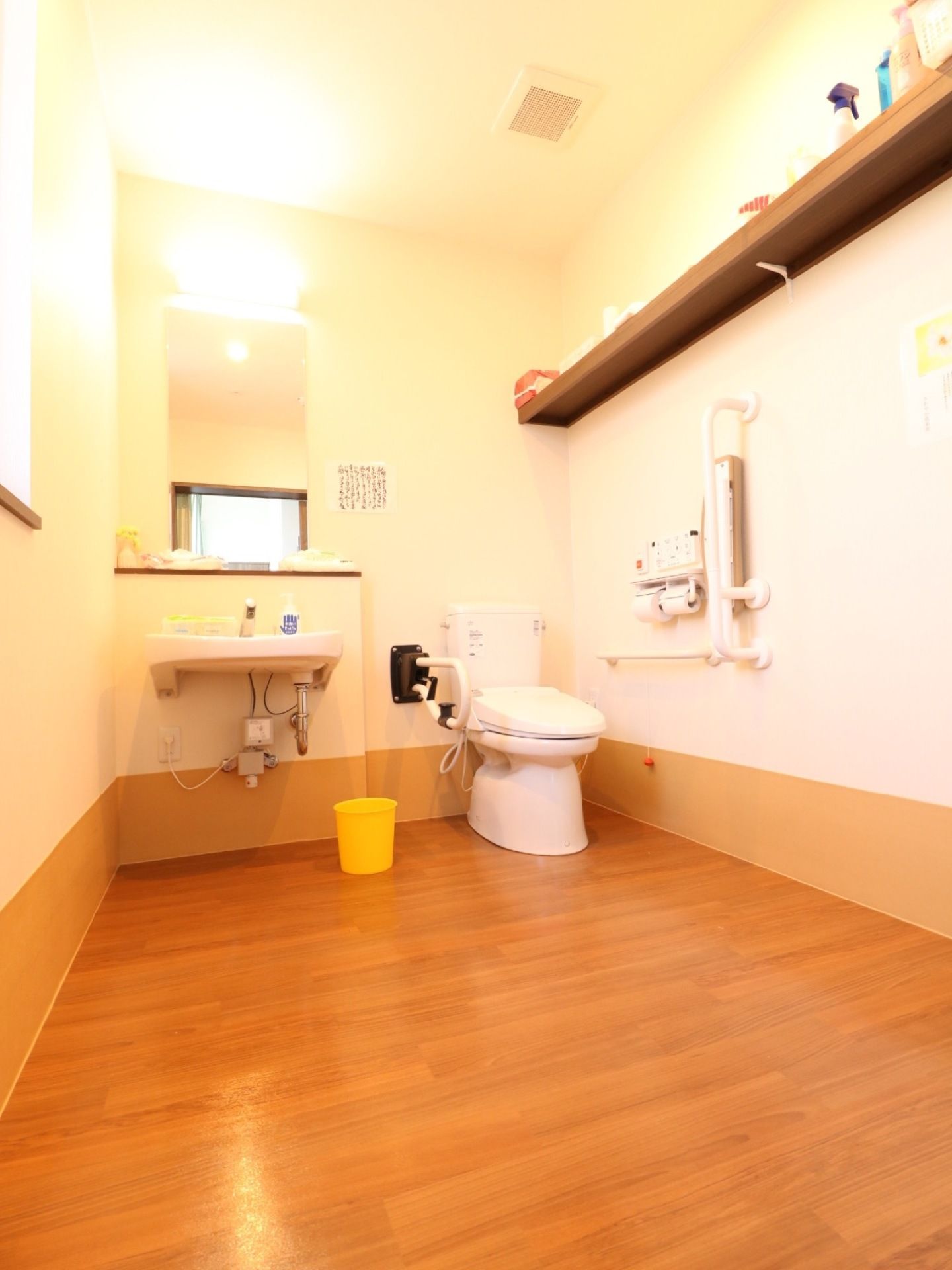 明るく開放感のあるトイレは、備品の棚を高い位置に設置している。奥行きのある造りで、車椅子をご利用の方も楽に移動できる。