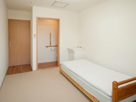 白を基調としたデザインの居室である。床は絨毯で、ベッドが設置されている。入り口のドアから、室内へ段差なく移動できる。