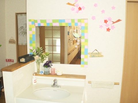壁にかわいい飾り付けをした、鏡付きの清潔感のある洗面台