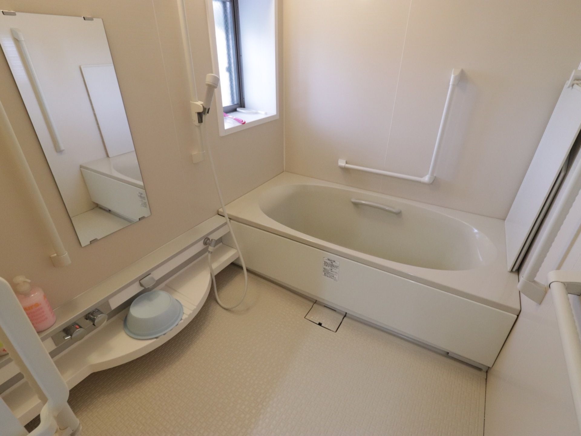 個浴タイプの浴室である。L型とI型手すりが壁に設置されており、シャワーはスライドバーに取りつけられている。