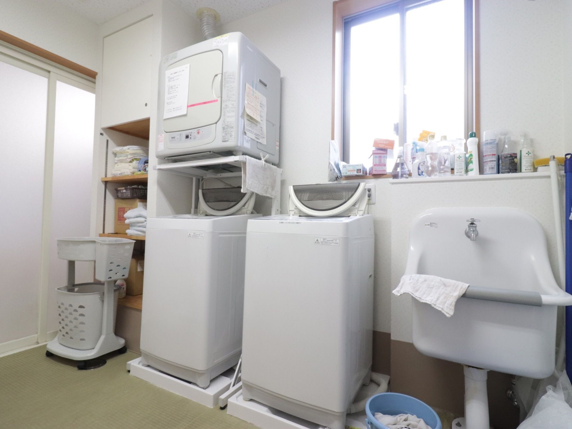 2台の洗濯機と乾燥機が設置されている。となりには洗濯機で洗えないデリケートなものなどが洗える、広々した洗い場もある。