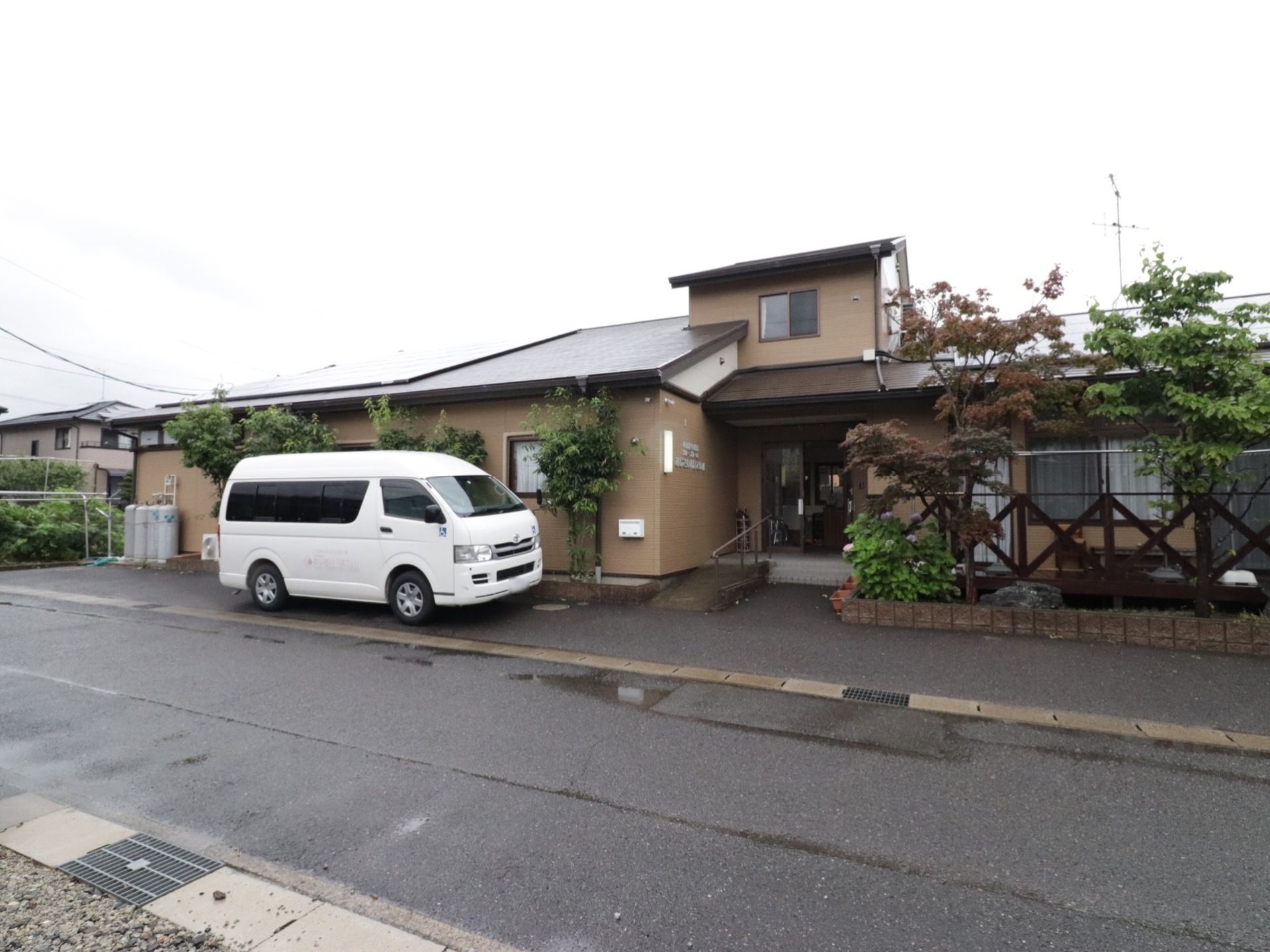 道路側に建つ施設である。外壁は茶系。施設の前はワゴンタイプの車が、縦列駐車で停められる広さを確保している。