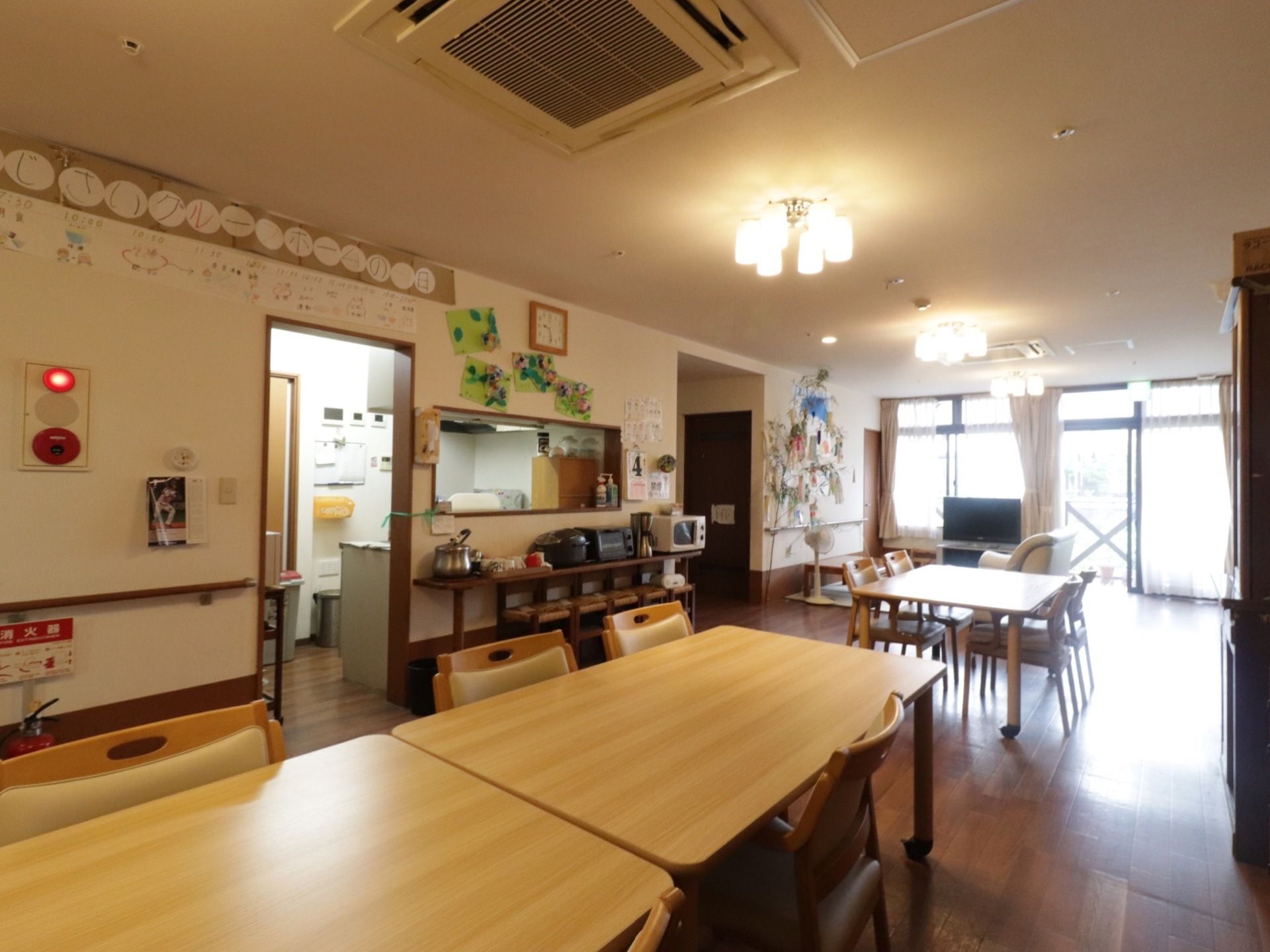 部屋からテラスを見渡せる共有スペースである。木製のテーブルと椅子が設置されている。壁には茶色の手すりを完備。