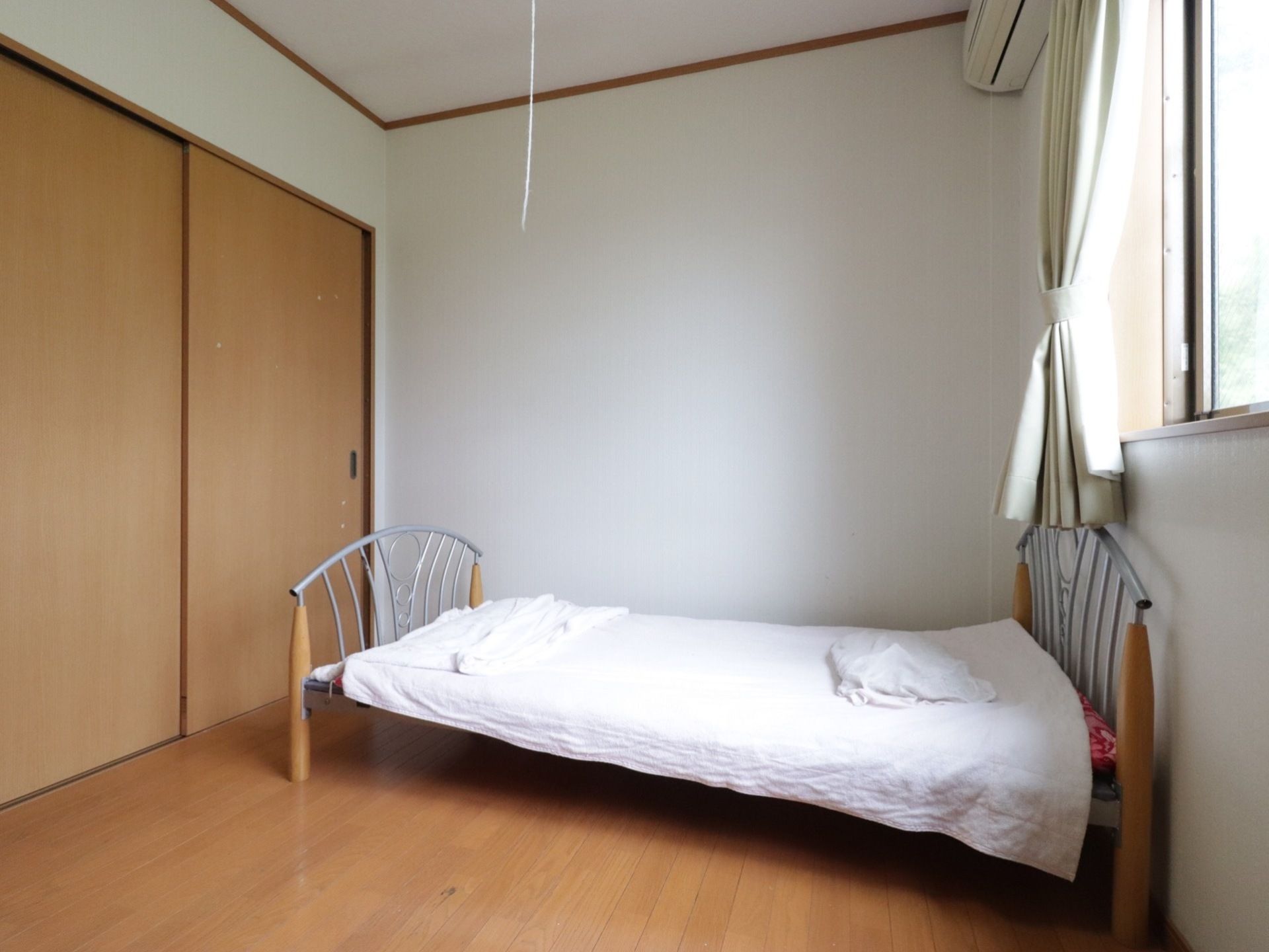 日当たりの良い１人用居室である。壁際にシングルベッドが置かれている。床は明るいカラーのフローリングである。