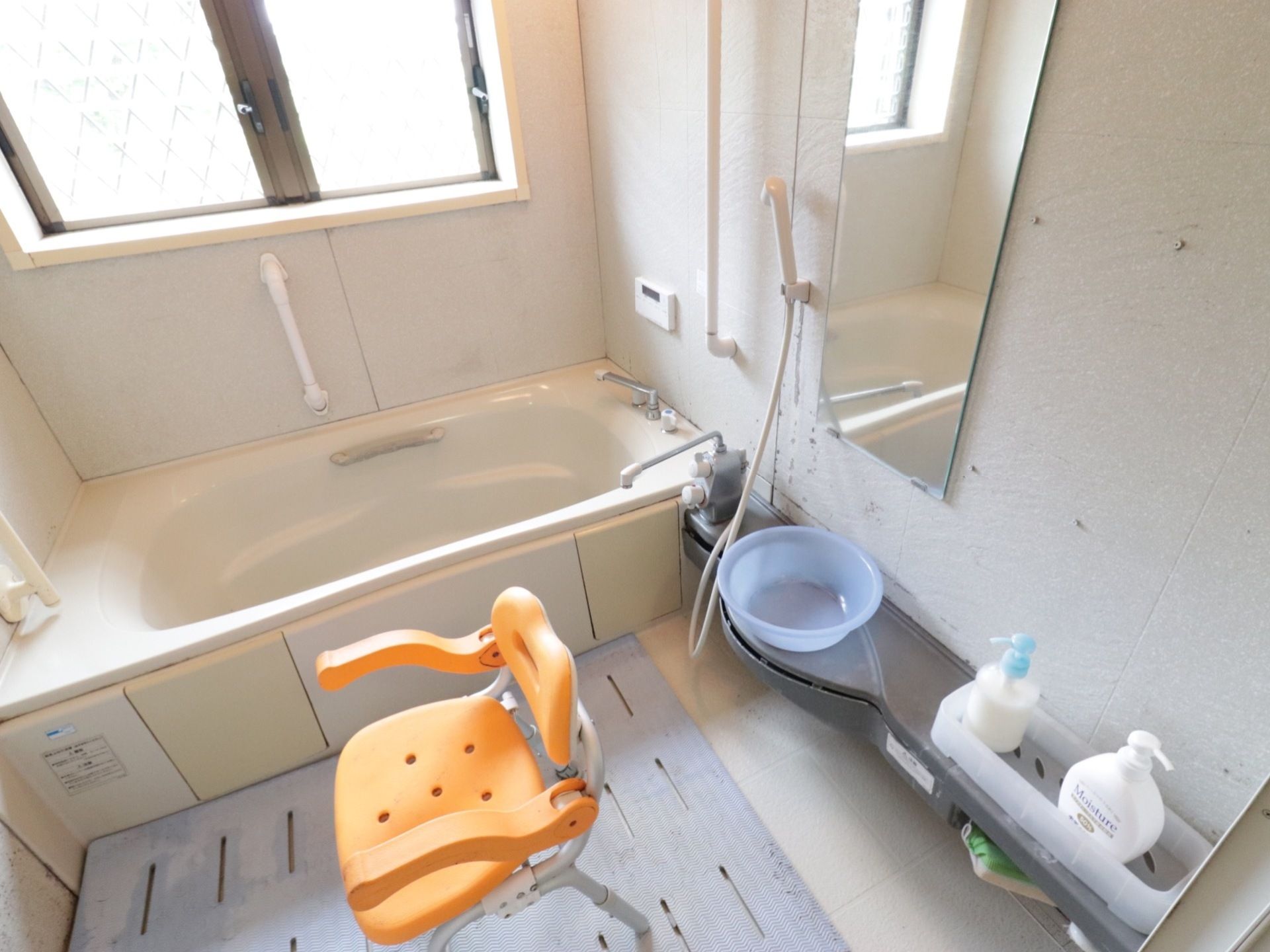 １人用の浴室にシャワーチェアがある。床に滑り止めのマットを敷き、壁面に手すりを取り付け安全に配慮している。