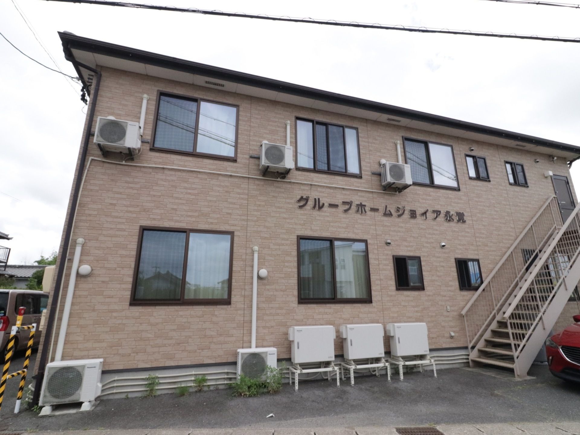 落ち着いたライトブラウンの２階建てである。各部屋にエアコンを完備している。２階から外へ出られる外階段がある。