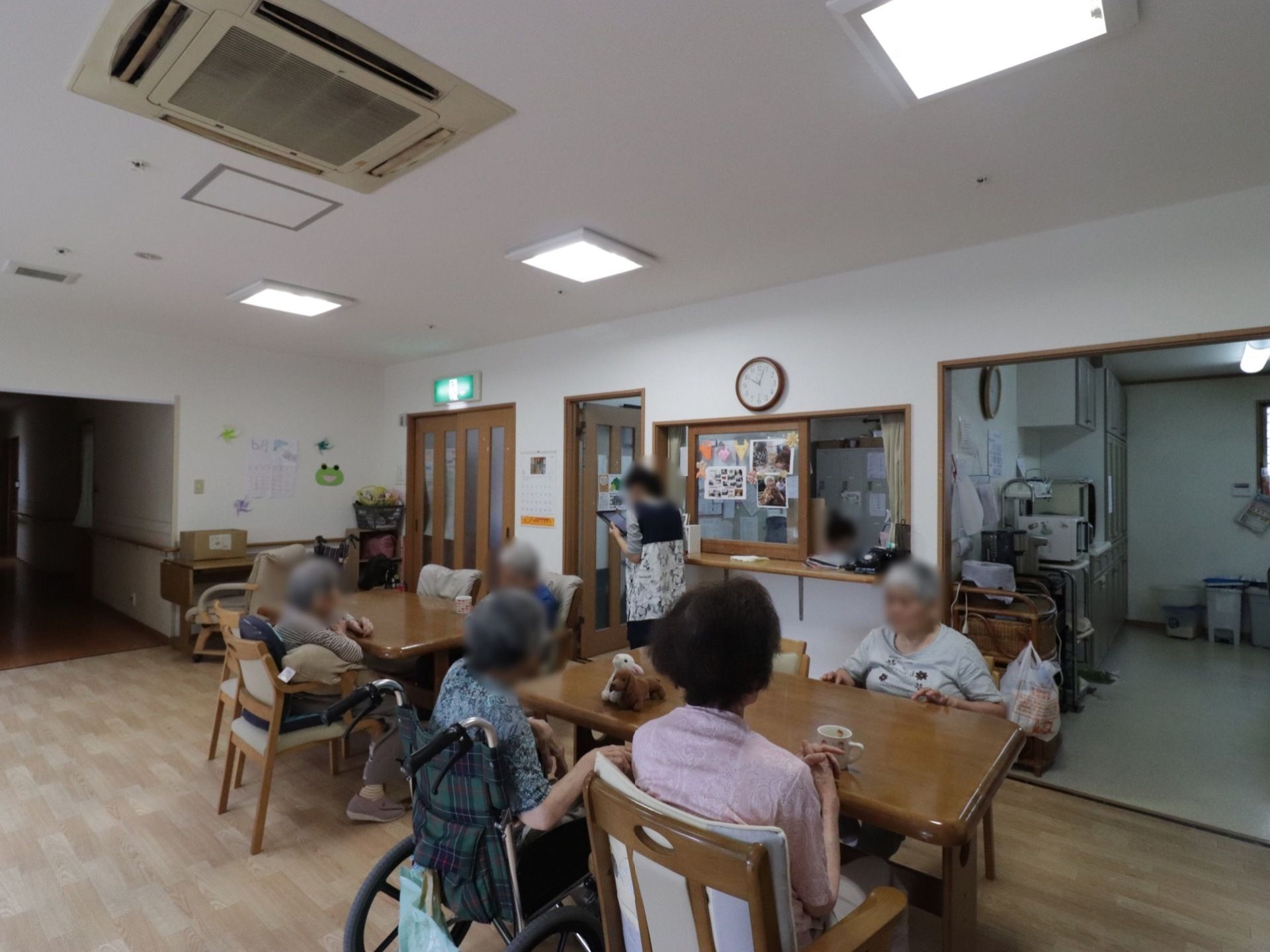 共有スペースの天井には全方向に送風される空調が整えられている。室内に設置されたテーブルには入居者様が腰を落ち着け、思い思いに過ごしている。