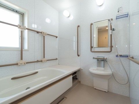 ユニットバスタイプの浴室に窓が設置されている。窓からの光と２つの点灯した照明により、浴室内はとても明るい。