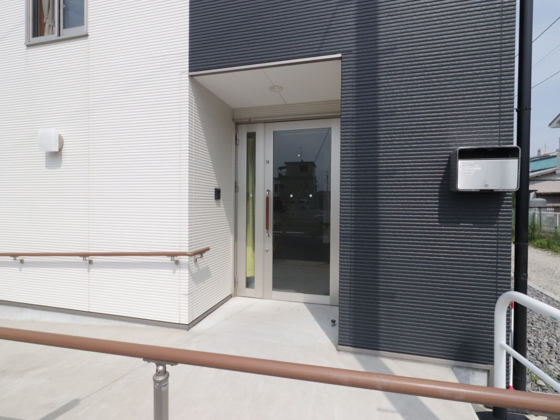 施設の入口扉は引き戸式であり、全面にガラスが張られている。両側の壁に手すりが備えつけられた入口までの通路は、横幅の広い設計である。
