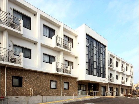 ３階建ての建物で１階はレンガ調で２階から上は白い塗装がされている外観