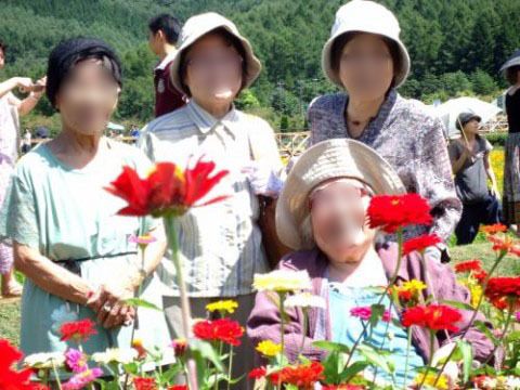 帽子をかぶり、花と一緒に写真を撮る4人の女性入居者
