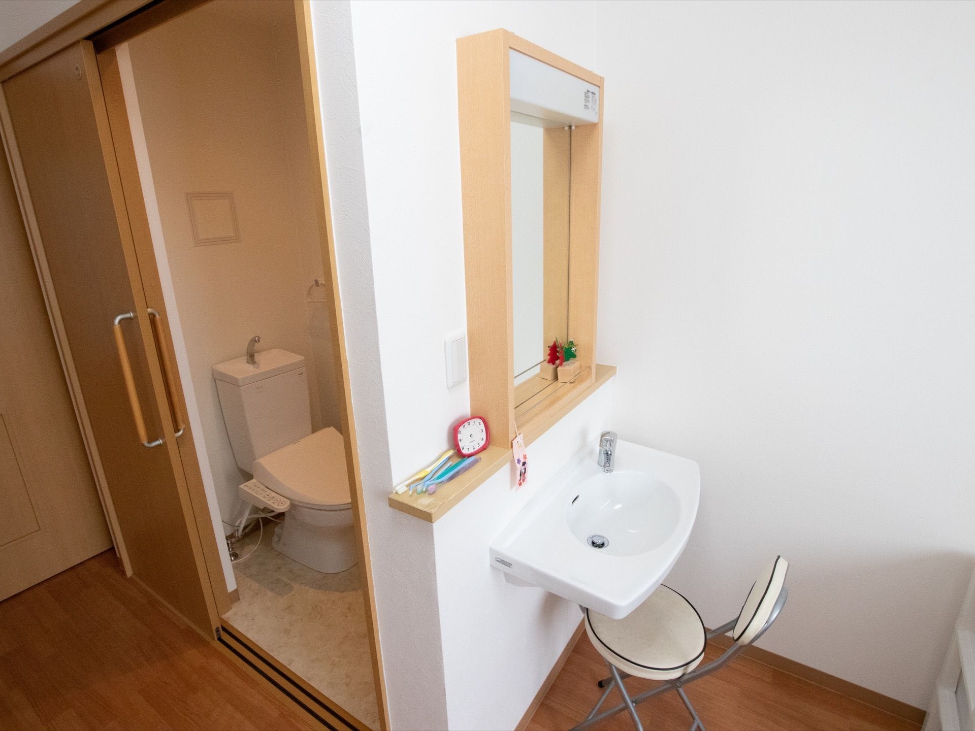 居室のトイレは、引き戸タイプの扉の中に設置されている。トイレとは別に、洗面台がある。大きな鏡もついている。