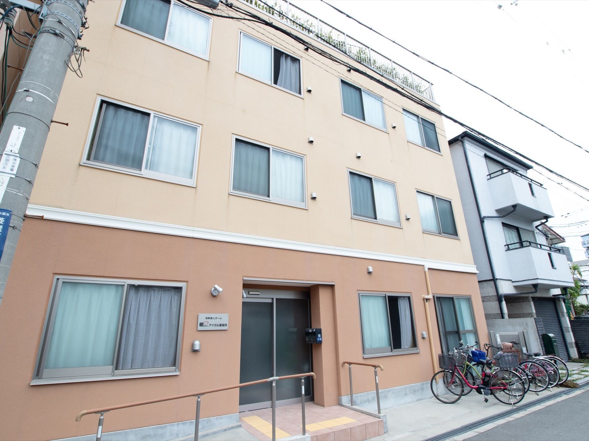 ツートンカラーの３階建ての施設である。玄関前にはスロープがある。通りからでも屋上庭園の緑を見ることができる。