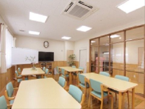 テレビやホワイトボードが置かれた空間。天井には複数の照明が取り付けられており、窓からはあたたかい光が差し込む。