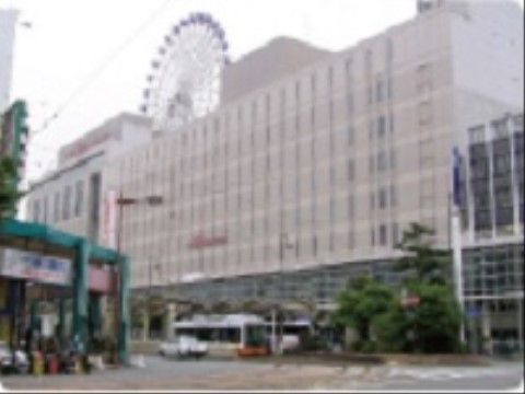 ターミナル駅周辺の写真である。建物前にはバスが停車しており、後ろに大きな観覧車が見える。道路真ん中に木が植えられている。