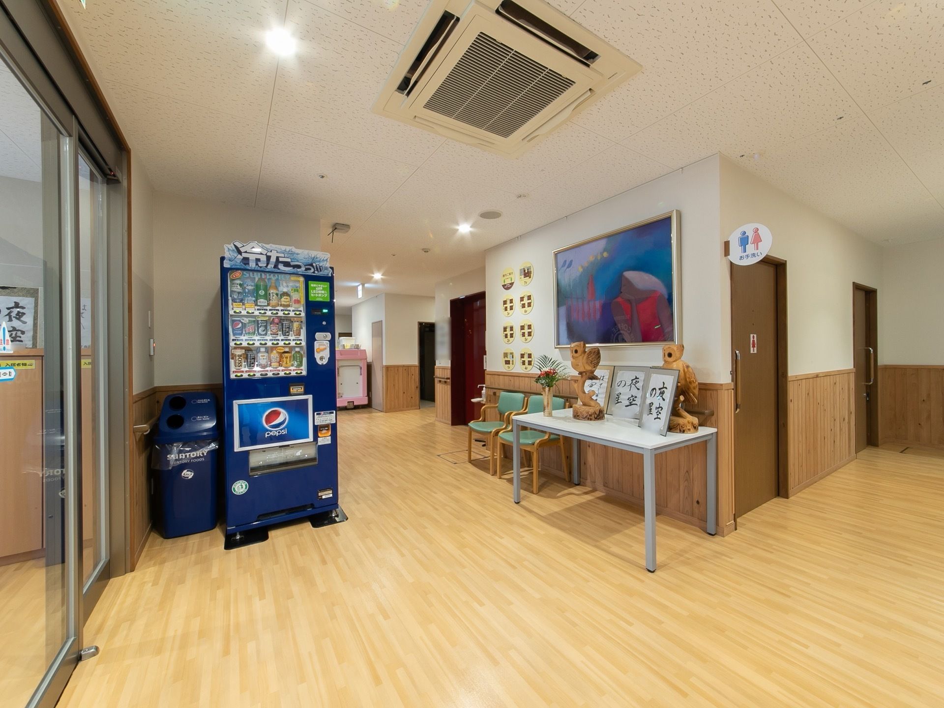 玄関を入ると、左手に飲料の自動販売機が設置されている。壁際に置かれたテーブルの上に書道などの作品が飾られている。