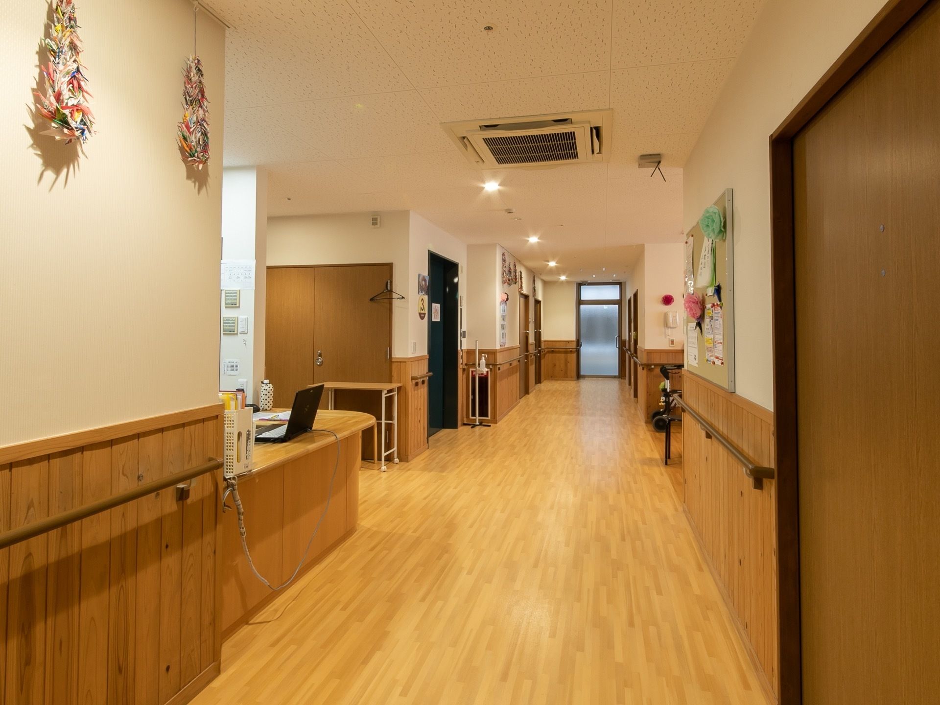 通路の両側には手すりが設置されており、床は段差のないバリアフリーである。壁には掲示板やクラフト作品などが飾られている。
