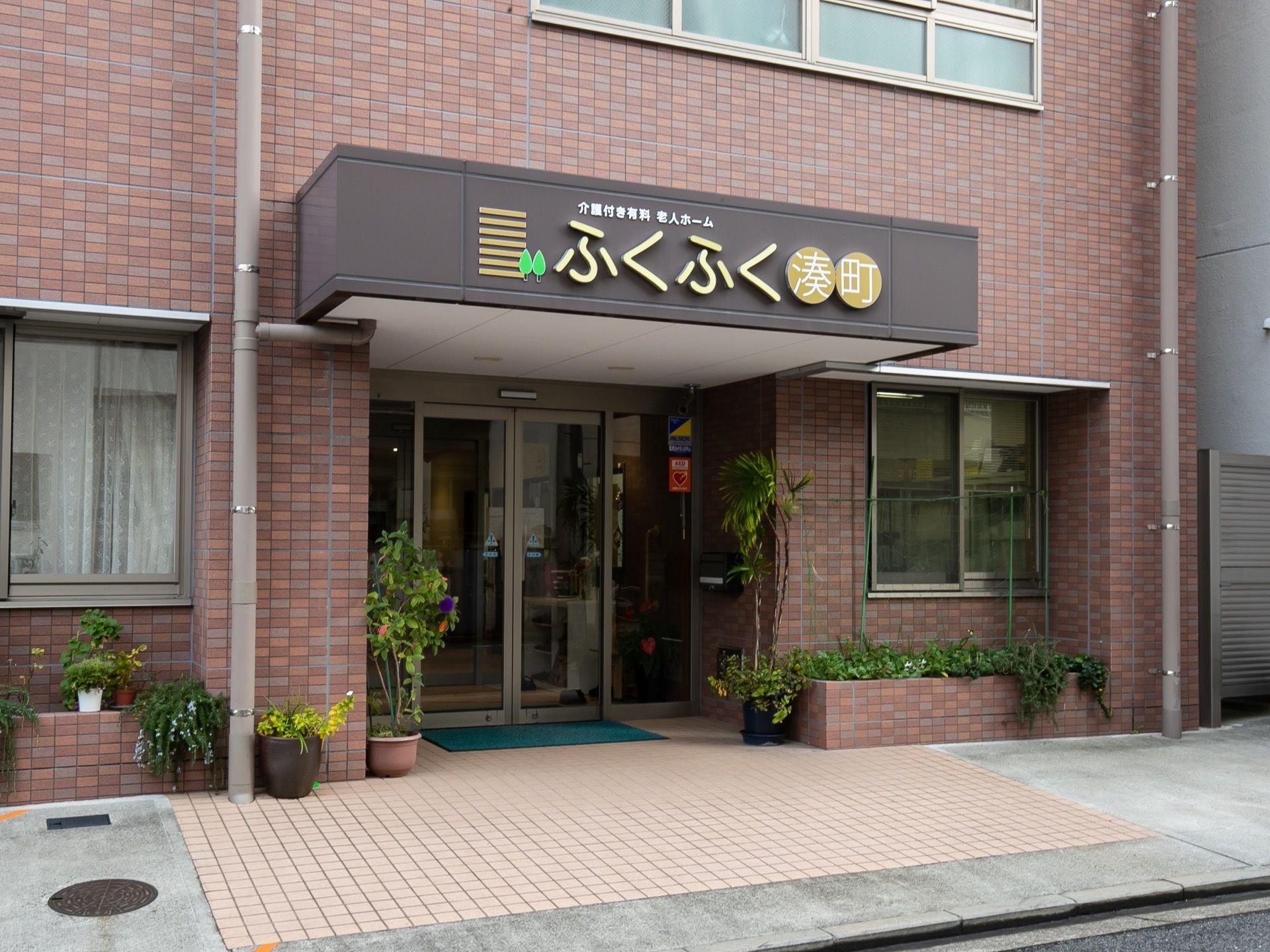 レンガ調の落ち着いた雰囲気の外観で、玄関わきには植物が置かれている。施設名が大きく表示されていて、見やすい。