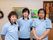 襟のついた水色の制服を着たスタッフが３人並んで写っている。後ろの白い壁には、リースや絵が飾られている。