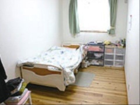 フローリングの居室で、木目の綺麗な床である。ベッドの前には小さなマットが敷いてあり、起き上がった時に足を置くことができる。