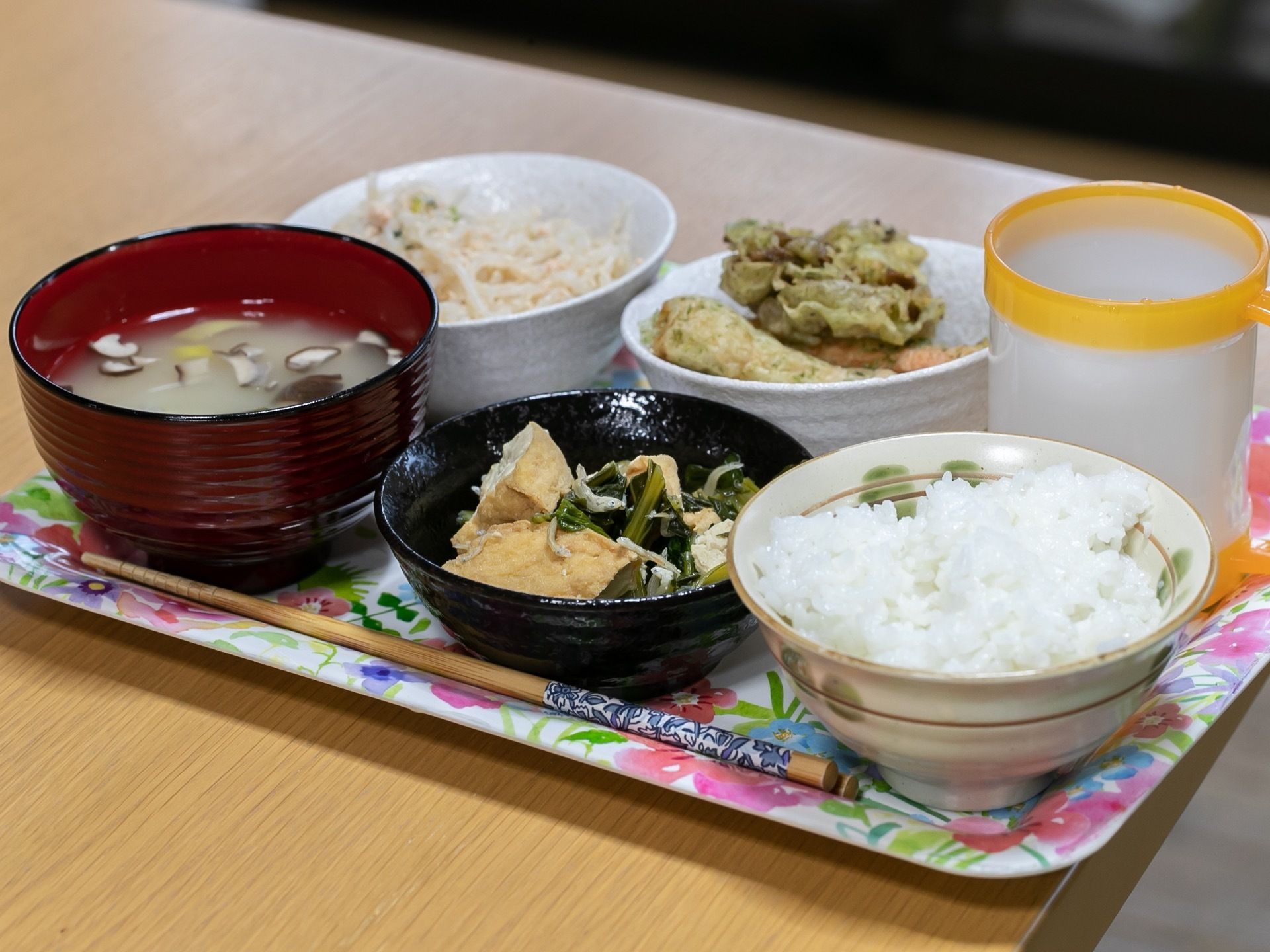 ある日の給食である。白ご飯や厚揚げと小松菜の煮物、てんぷら、みそ汁、野菜サラダである。野菜が中心でボリュームがある。