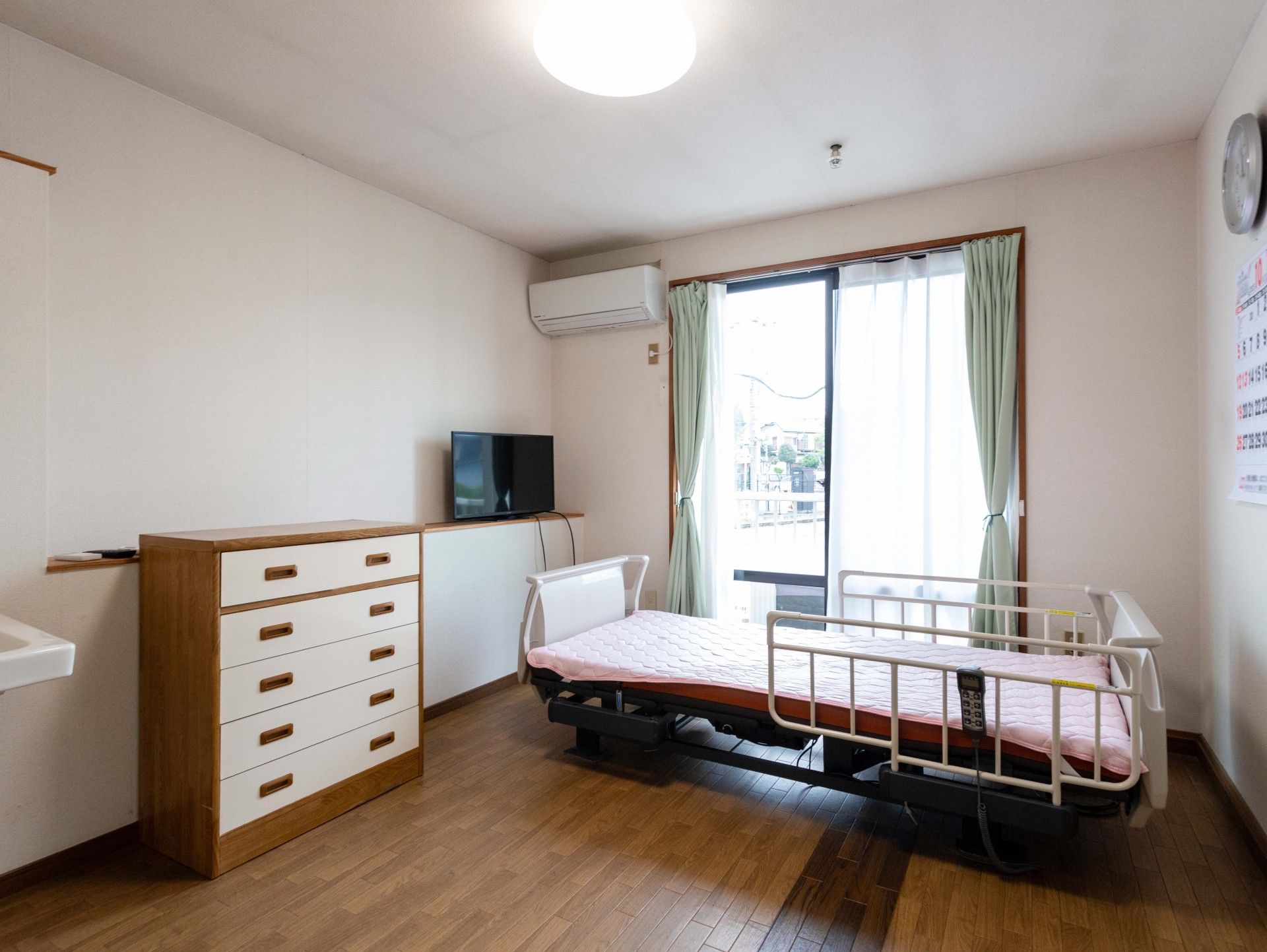 黄色いカーディガンを着て車椅子に座っている高齢女性と介助をする女性ヘルパー