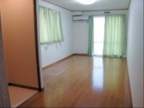 居室には、愛用する家具や家電を持ち込むことができる。２か所ある窓には、緑色のカーテンが掛けられている。