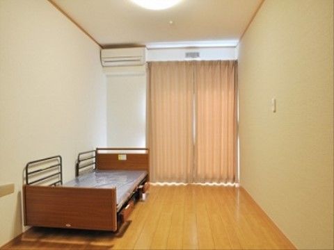 掃出し窓があり、日当たりも良好で明るく、床面はバリアフリー仕様のフローリングである。ベッド、エアコンを完備している。