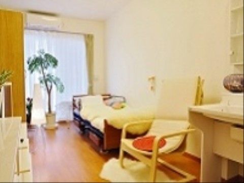 窓際には観葉植物が飾られている。ベッドの足元にはハイバックチェアが1脚用意されている。洗面台もある。
