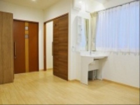 床はフローリング、壁は白色で統一されている。2枚の茶色い扉がある。窓の近くには鏡付きの洗面台が設置されている。