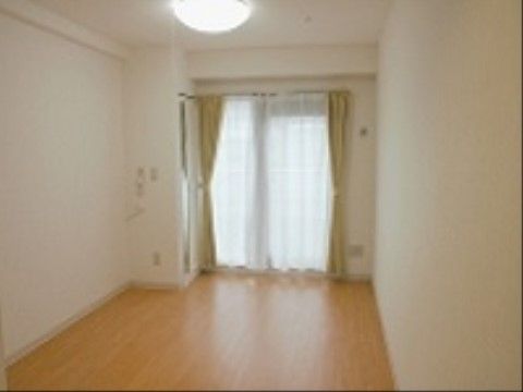 大きな窓がついた、広々とした居室。明るい電気と柔らかい色味のフローリングで、温かみのある空間となっている。