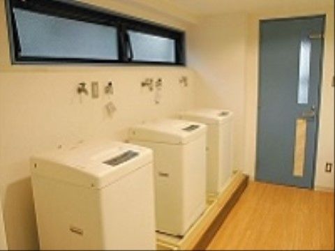 内装は白く、床には段差がないランドリールーム。室内には洗濯機を3台設置しているので、待ち時間なく洗濯ができる。