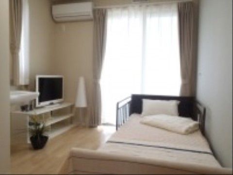 ２カ所に設けられた窓から明るい日が射す居室にはエアコンが設置され、ベッドやテレビなどの家財道具が置かれている。