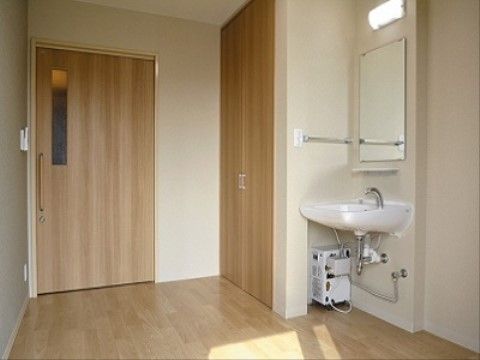 室内に設けられた洗面台の正面には、鏡と照明が設置されている。隣には収納家具が据え付けられていて便利である。