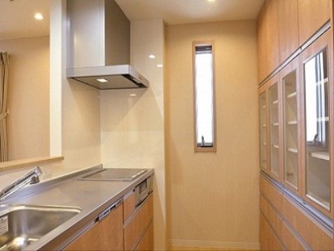 清潔感のある対面式のキッチンは、木調のドアを使用したモダンでシンプルなデザインである。収納スペースも十分に設けられている。