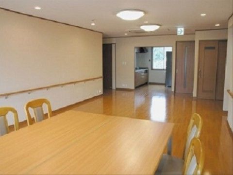 広い空間にダイニングセットがある。両側の壁には手すりが付いている。廊下を挟んで突き当りに台所がある。